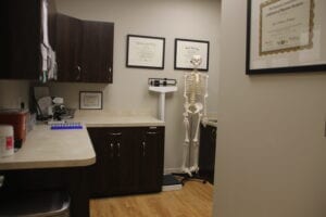 A white room with dark wooden cabinets, equipment, and a skeleton