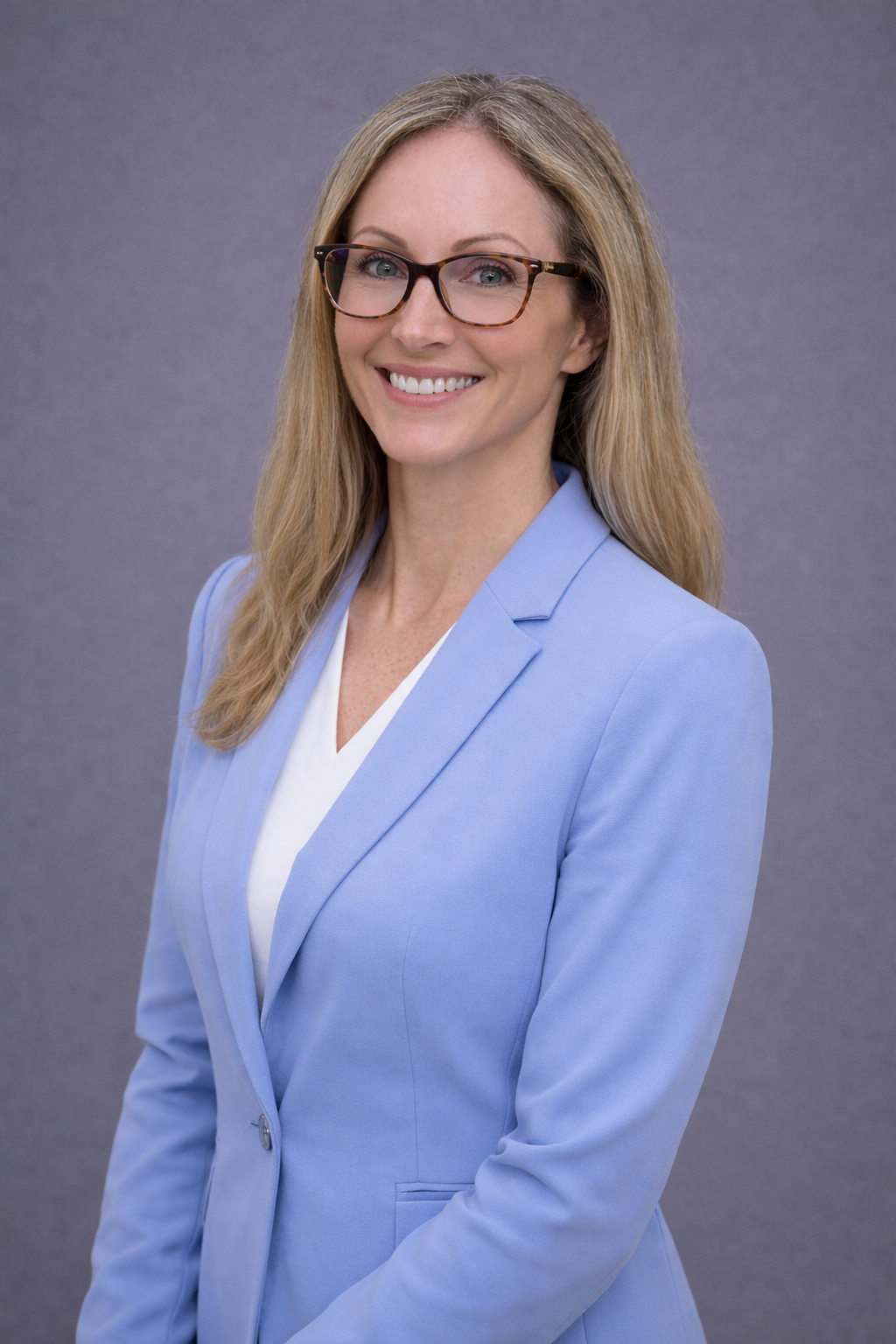Professional woman in a light blue blazer smiling.