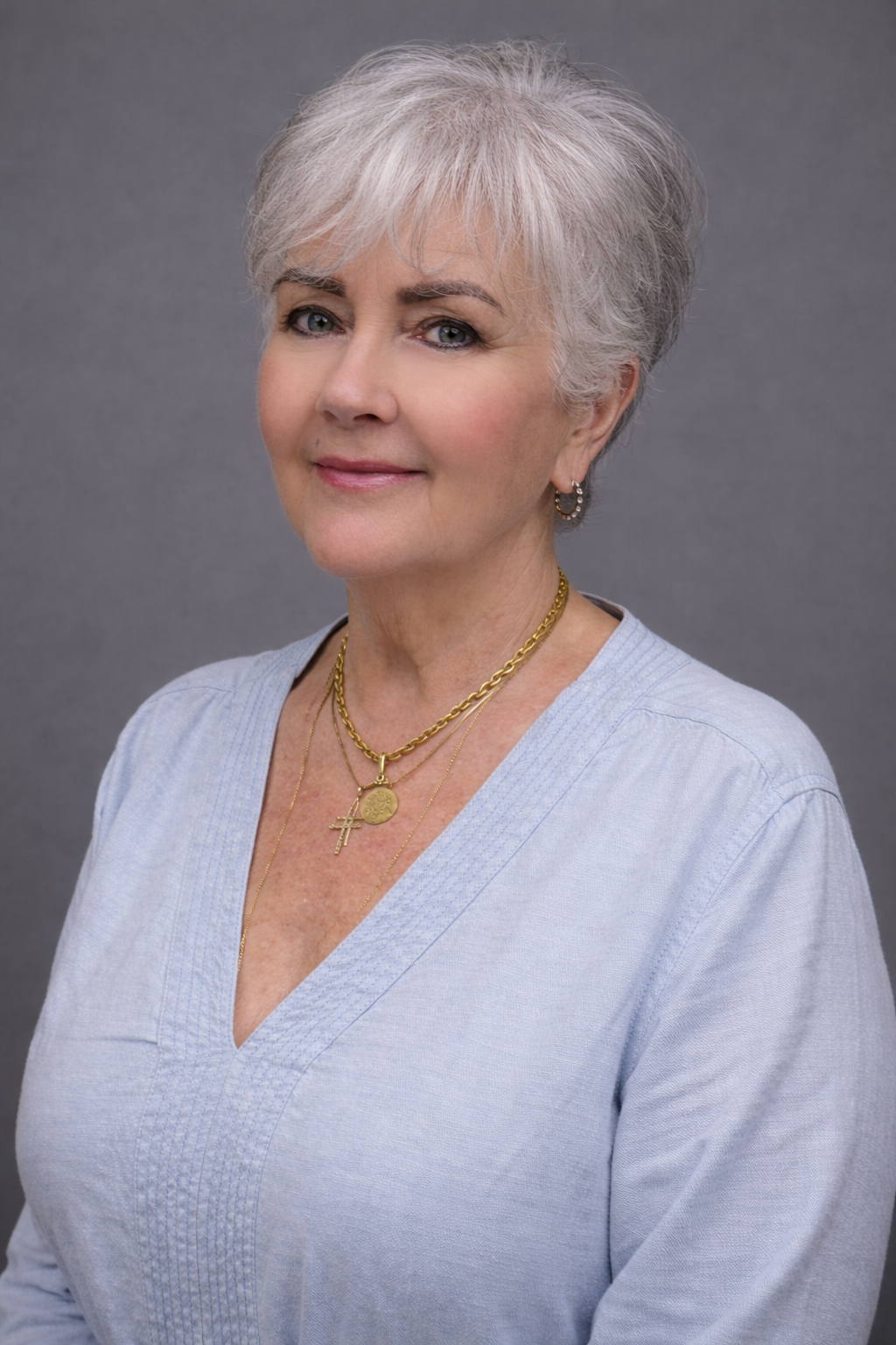 Portrait of a confident older woman with short gray hair and a light blue blouse.