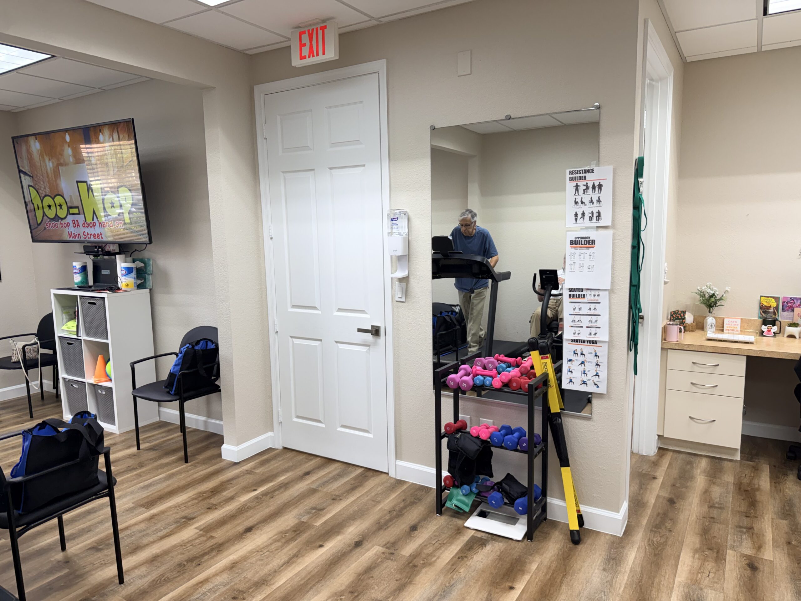 Corner of a room with a mirror, cleaning supplies, and chairs.
