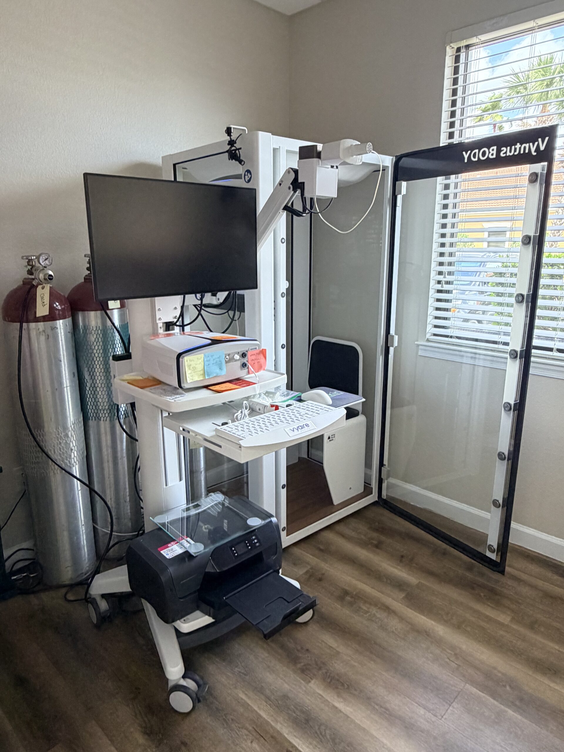Medical imaging equipment setup with monitor and control panel in a clinical room.