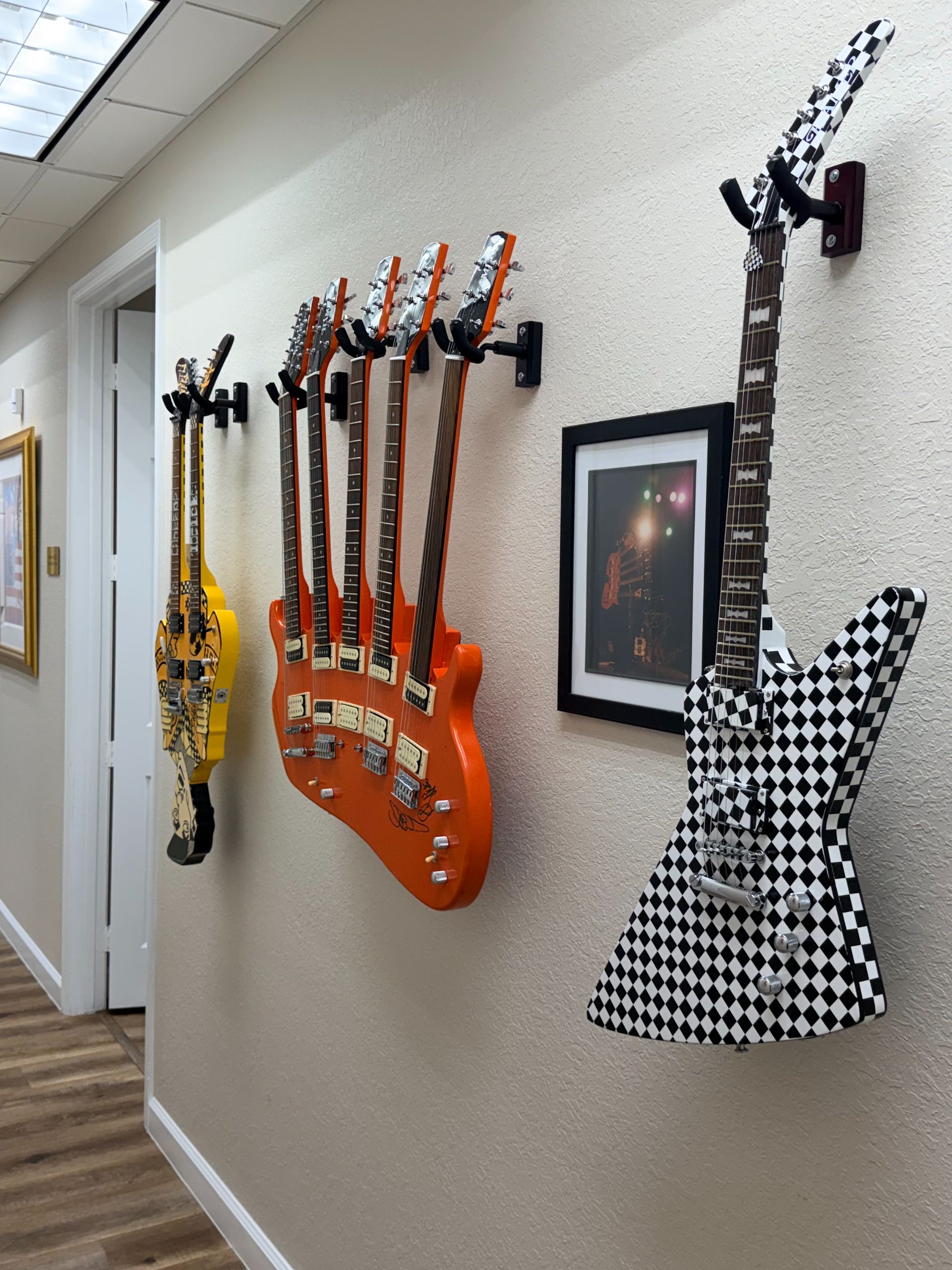 A hallway wall decorated with unique, artistic guitars in various designs and colors.